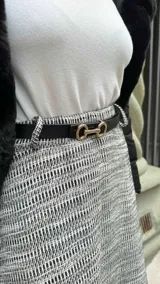 Cinto negro de cuero con hebilla dorada con forma de estribo.