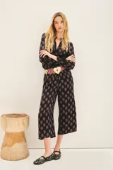 Pantalón capri negro con estampado floral, corte regular, bolsillos laterales y elástico en la parte trasera.