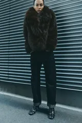 Abrigo corto marrón de pelo sintético, con cuello solapa, manga larga, bolsillos delanteros, forro interior y cierre frontal con botón.