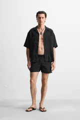 Short de baño negro de tejido técnico, con cintura elástica ajustable con cordón, bolsillos laterales y bolsillo trasero.