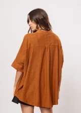 Camisa marrón con calados, escote en V, abotonada y manga 3/4.