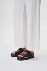 Sueco de cuero color marrón con plataforma y detalle de tachas plateadas.