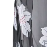Kimono negro de gasa semitransparente con estampado floral blanco, calce suelto, cordón ajustable en la cintura y mini borlas decorativas en el borde.