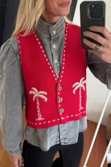 Chaleco tejido color crema con diseño de palmeras verdes, escote en V y cierre con botones.