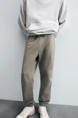 Pantalón jogger negro de corte slim fit, confeccionado en tejido de algodón con cintura elástica ajustable con cordón, bolsillos frontales y traseros de vivo, y bajo con puño elástico.