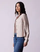 Chaqueta color beige de lino y rayón, con cuello mao, cierre frontal con botones y bolsillos delanteros.