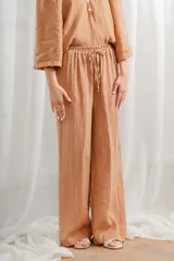 Pantalón de lino blanco, de corte ancho y tiro alto, con cintura elastizada y cordón ajustable.