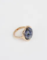 Anillo dorado con piedra redonda azul con manchas grises.
