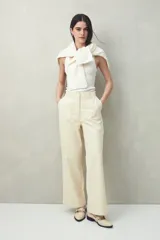 Pantalón de vestir color crema, de corte recto y tiro alto, con bolsillos delanteros grandes.