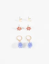 Set de tres pares de aros plateados: un par de aros tipo botón con forma de media luna, un par de aros tipo botón con forma de flor y cristales verdes, y un par de aros colgantes con forma de racimo de uvas rojas.