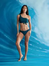 Conjunto de bikini color azul petróleo, con corpiño asimétrico de un solo hombro con nudo en el centro y bombacha colaless.
