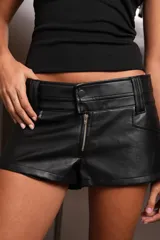 Short negro de cuerina, tiro bajo con doble cintura y cierre frontal con cremallera metálica YKK.