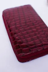 Billetera marrón con estampado de piel de serpiente, cierre perimetral, múltiples ranuras para tarjetas, documentos y billetes, y bolsillo interior con cierre para monedas.