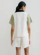 Camisa de manga corta color crudo con estampado de lunares negros, cuello clásico, cierre frontal con botones negros y dos bolsillos de parche en el pecho.