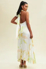 Vestido midi blanco con estampado floral en tonos verdes y amarillos. Diseño plisado con cuello halter y abertura en el pecho.