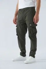 Pantalón cargo color marrón, corte slim, con cierre y botón en la cintura, pasacintos y bolsillos cargo con botones.