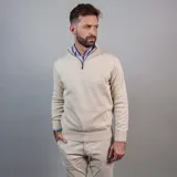 Buzo color beige de algodón y poliéster, con cuello alto y cierre metálico hasta la mitad del pecho.