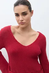 Sweater de tejido de punto negro, con escote en V pronunciado y mangas largas acampanadas. Presenta un lazo ancho anudado a la cintura.