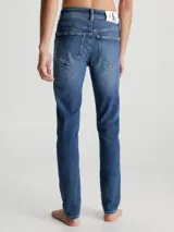 Jeans de denim elástico azul con efecto lavado, corte skinny, tiro bajo, cinco bolsillos y cierre con cremallera.