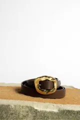 Cinturón color crema con hebilla cuadrada dorada con diseño irregular.