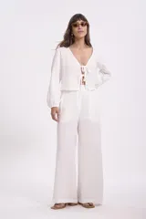 Blusa blanca de manga larga con escote en V y lazos para atar en el frente.