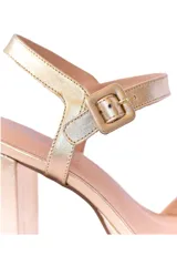 Sandalias de tacón alto color dorado, con plataforma y tira delgada ajustable al tobillo.