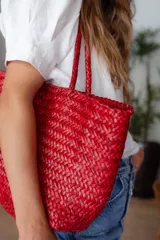 Bolso tipo tote de cuero vacuno, completamente trenzado a mano. El color es marrón oscuro, casi chocolate. Posee dos asas de hombro trenzadas.