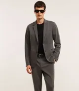 Pantalón de vestir gris con textura, corte slim, con trabillas en la cintura y cierre por botón y cremallera.