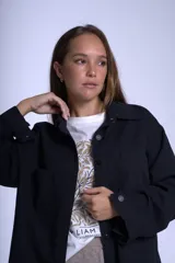 Sobrecamisa negra de gabardina con cuello camisero, cierre frontal con botones, mangas largas con puños abotonados y bolsillos de parche en el pecho.