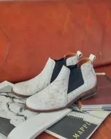 Botines Chelsea de cuero negro con elástico lateral y suela marrón.