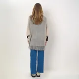 Poncho de acrílico color beige con detalles en gris y flecos en el borde inferior.