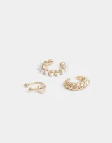Set de tres earcuffs dorados: uno liso con textura, uno con detalle de corazón y uno con perlas.