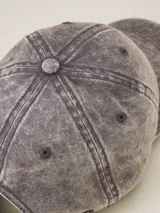 Gorra de gabardina color gris oscuro con visera curva y etiqueta con logo de la marca en el lateral.