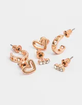 Set de tres pares de aros bañados en oro rosa: un par de argollas con strass, un par de aros pasantes con forma de corazón y un par de aros con tres strass.
