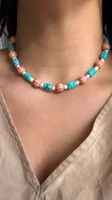 Collar corto con cuentas de piedra reconstituida en color turquesa, cuentas de cerámica acanaladas en color rosa y perlas de río.