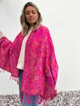 Pañuelo fucsia con estampado de arabescos en tonos naranja y violeta, con flecos en el borde.