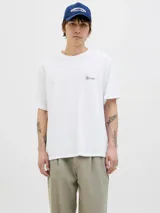 Remera blanca de algodón con cuello redondo y mangas cortas. Estampado en la espalda con una sombrilla de playa, una reposera y la frase "Bella Vita".