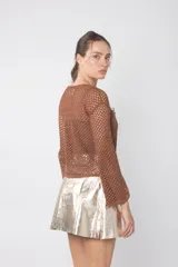 Top de tejido calado color marrón con mangas largas acampanadas y detalle de broches decorativos en el escote.