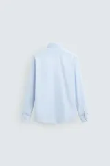 Camisa celeste de corte regular, con cuello italiano, mangas largas con puños abotonados y cierre frontal con botones.