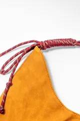 Bolso marrón con forma de media luna y asa de soga trenzada en rojo y blanco.