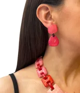 Aros colgantes de resina rosa con piezas geométricas y ajuste de perforación en acero hipoalergénico.