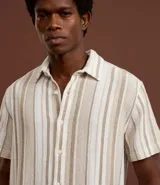 Camisa de manga corta para hombre marca Marfinno, confeccionada en tejido texturizado de mezcla de algodón y poliéster. Presenta un diseño de rayas verticales en tonos beige, gris y bordó, con cuello tradicional y cierre frontal mediante botones.