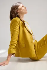 Blazer color mostaza de lino con corte estructurado, solapas con pespuntes y bolsillos con solapa.