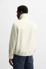 Sobrecamisa color crudo de corte regular fit, confeccionada en tejido con mezcla de viscosa. Tiene cuello solapa, manga larga con puños abotonados, bolsillo de parche en el pecho, bajo ajustable con cordones y cierre frontal con botones.