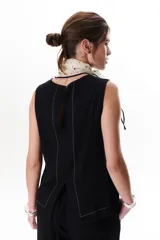 Top sin mangas color terracota con cuello redondo y bolsillo frontal. Presenta costuras a contratono en blanco que definen los bordes y el bolsillo.