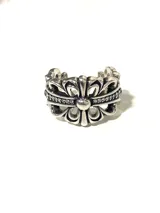 Anillo plateado con diseño de flor de lis y pequeños cristales incrustados.