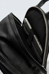 Mochila negra con acabado grabado, compartimento principal con cierre de cremallera, bolsillo frontal con cierre de cremallera, parte posterior acolchada con banda de sujeción para equipaje, asa de mano y dos asas de hombro ajustables.