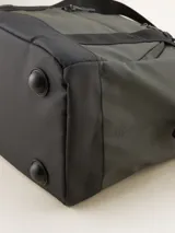 Bolso tipo duffel verde militar con base y detalles en negro. Tiene doble asa de mano y correa de hombro ajustable y extraíble. Cuenta con dos bolsillos frontales con cierre y logo de la marca en la parte inferior.