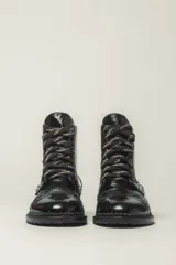 Borcego de cuero vacuno con acabado charol color negro, con cordones y suela de goma.