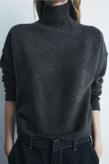 Jersey de punto color gris oscuro, de cuello alto y manga larga con terminaciones en rib.